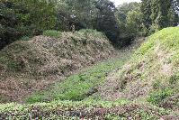 土と芝生の地面の真ん中がくぼみのようになっている紙屋城第二の空堀跡の写真