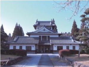整えられた植木に囲まれ,背景には青空を望む和風建築の資料館外観写真