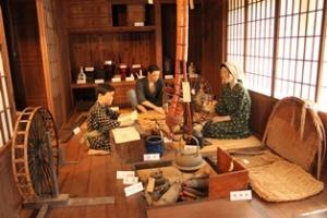 和服を着た家族の人形と人々の暮らしを再現した展示物が置かれた一角の写真