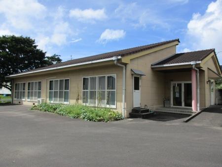 ベージュ色の壁とグレーの屋根が見える施設外観の写真