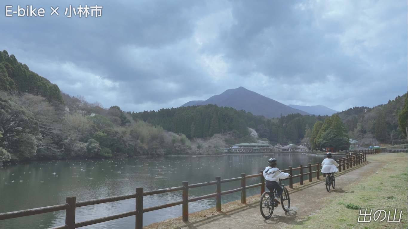 池のほとりを女性二人が自転車に乗って走っている様子