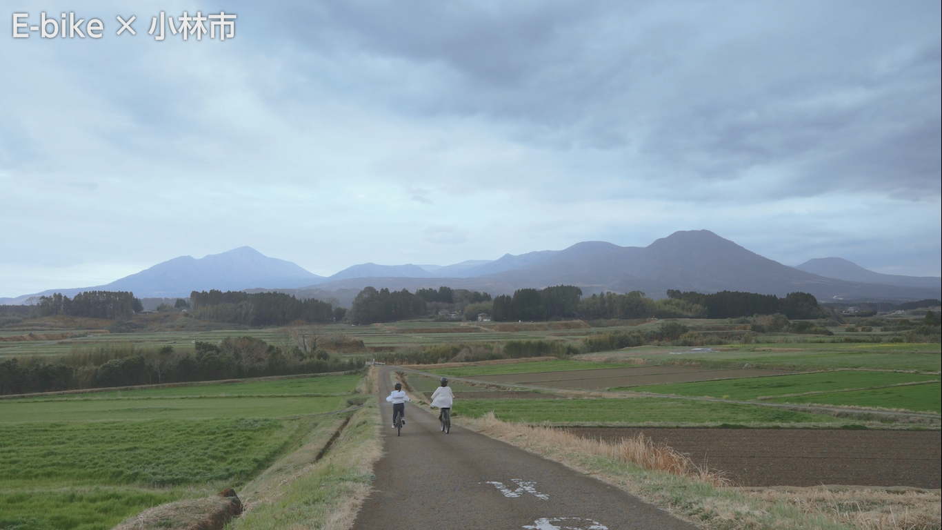 山に向かって道路を自転車で走る二人の女性