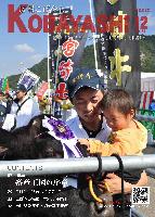 のぼりが並ぶ祭りの中、牛とふれあう親子の写真が掲載された広報こばやし12月号の表紙
