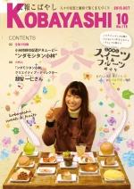 机に並ぶフルーツやスイーツが乗ったたくさんの皿を前に笑顔を浮かべる女性の写真が掲載された広報こばやし10月号の表紙