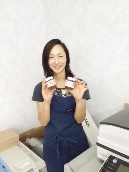 瀬尾さんがカメラに向かって瓶詰を2つ手に持ち笑顔を向けている写真