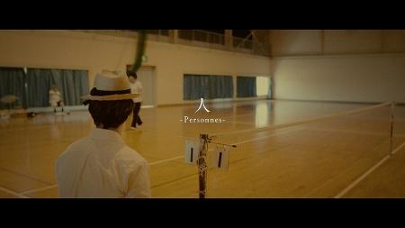 体育館でマイクの前に立っている男性を背後から撮影した写真