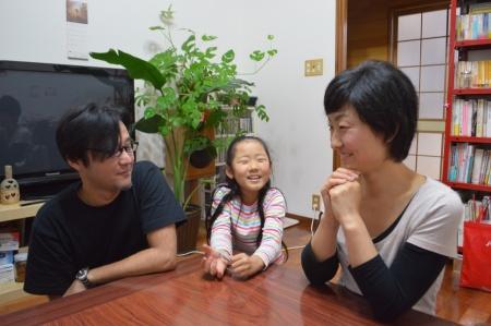 テレビや本棚のあるリビングで子供と大人が楽しそうに話している写真