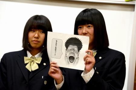 「なんだこれはっ!?」というフキダシがついた男性のイラストを持っている、二人の女子生徒たちの写真