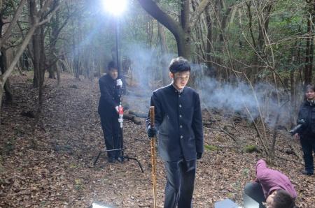 手に棒を持って立っている男子生徒と、その後ろでライトを当てている男子生徒の写真