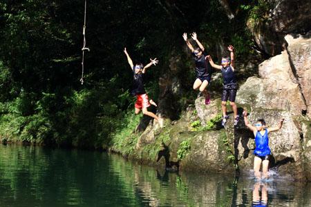 水中ゴーグルをつけた児童たちが元気よく川に飛び込む写真