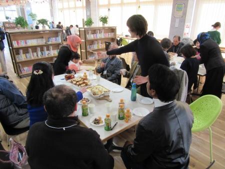 おいしそうな料理を囲んで笑顔で談笑する参加者たちの写真