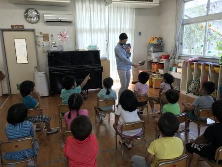 保育園内で先生のほうを見て指さしている園児たちの写真