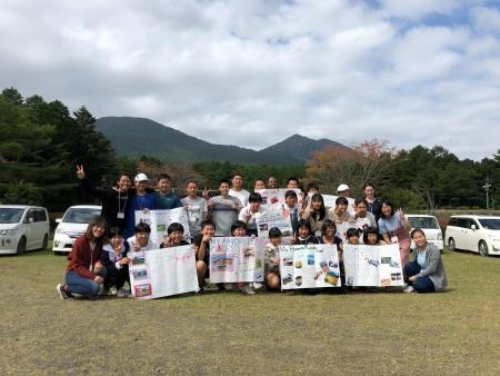 青空と車を背景にワールドキャンプ参加者たちが記念撮影をしている写真