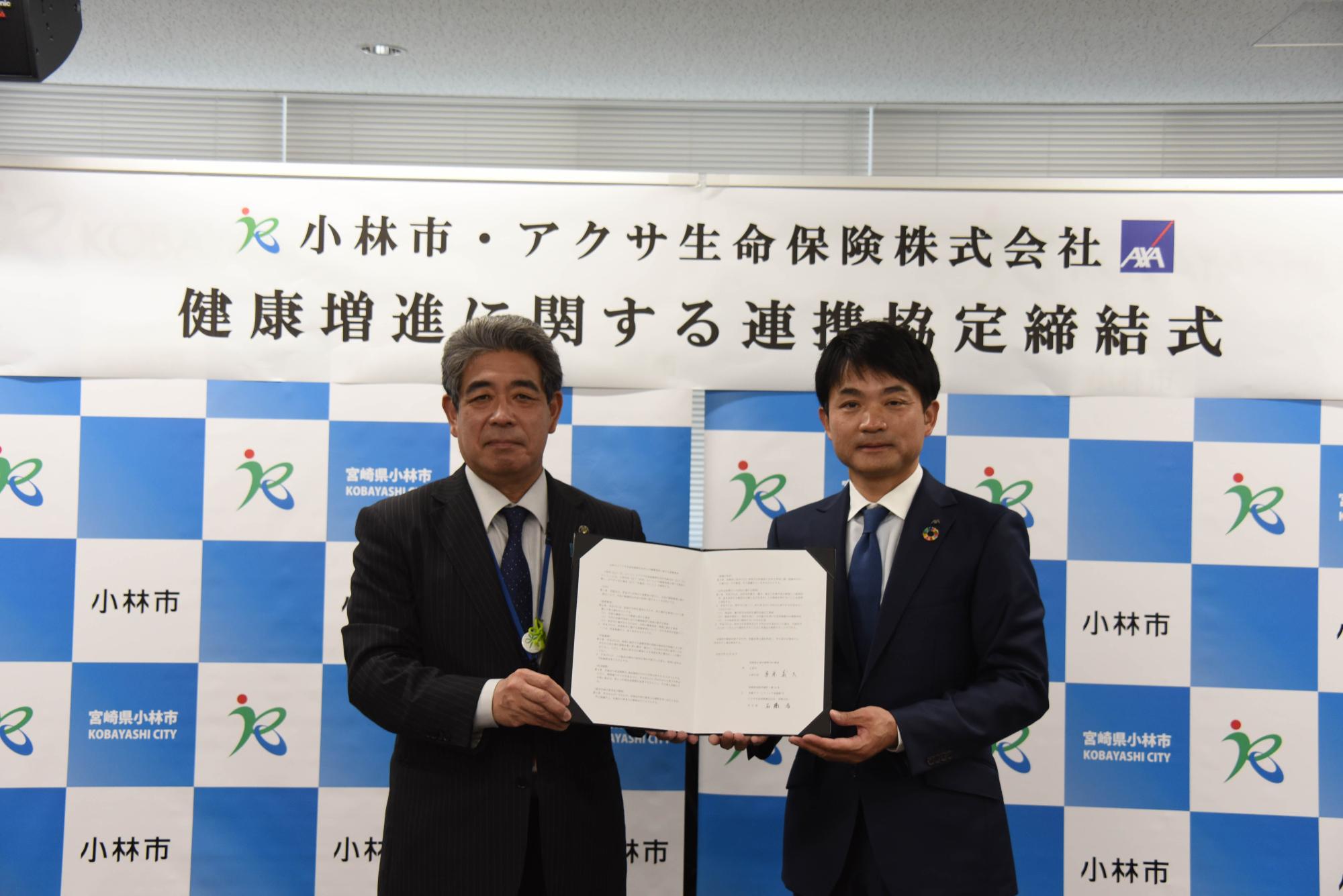 市長とアクサ生命保険株式会社宮崎支社長が協定書を持つ写真