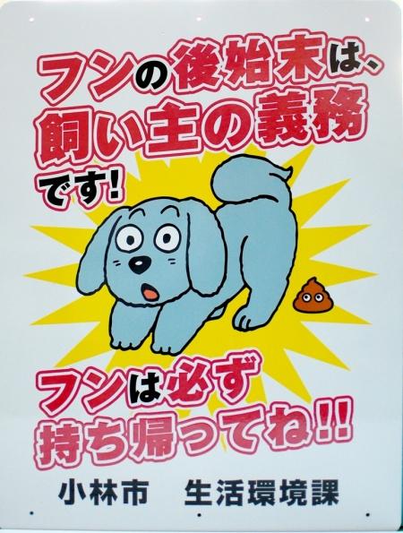 排泄したあとに驚いた表情をしている犬のイラストが描かれ、飼い犬のフンの後始末を促す看板の例