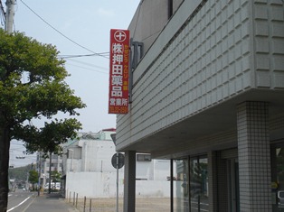 灰色の建物に押田薬品と書かれた赤い看板が取り付けられた写真