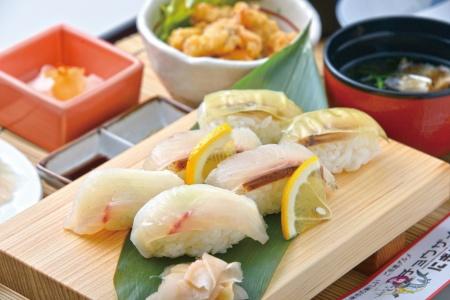 寿司下駄の上に綺麗に盛り付けられたチョウザメにぎりと小鉢、お吸い物などが写った写真