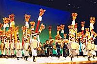 ステージの上で多くの演者が踊りながら和太鼓を奏でる写真