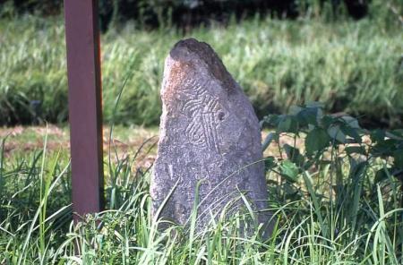 芝生の上に模様が刻まれた石碑が立っている写真