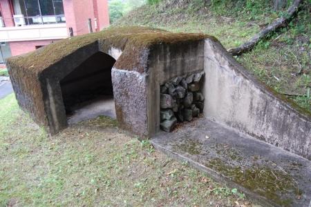 傾斜のある地面と、石で出来た古墳模型の入り口部分の写真
