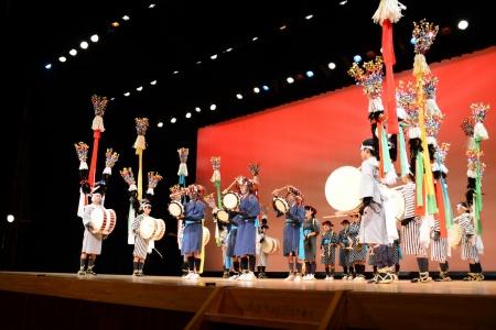 和服に身を包んだ演者たちがステージの上に並んで太鼓を奏でている写真