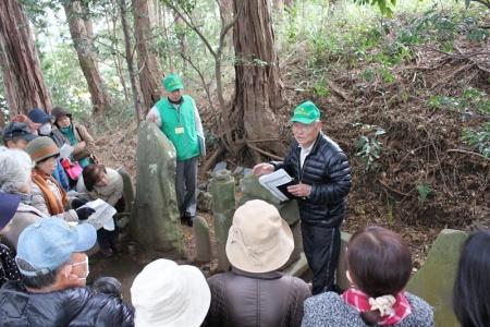 帽子を被ったガイドの男性2名が山道の途中で参加者に向けて話かけている写真