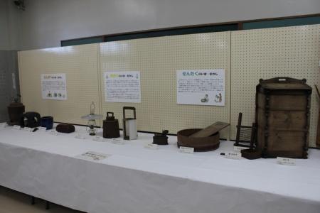 白いクロスが敷かれたテーブルの上に説明資料と民具が置かれている写真