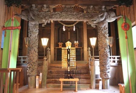 高浮彫りの柱が灯篭の明かりで照らされている霧島岑神社雲龍巻柱の写真