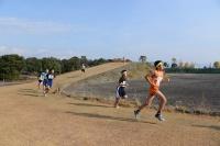 総合運動公園内にあるクロスカントリーコースでオレンジのユニフォームを着た選手を先頭に選手たちが走っている写真