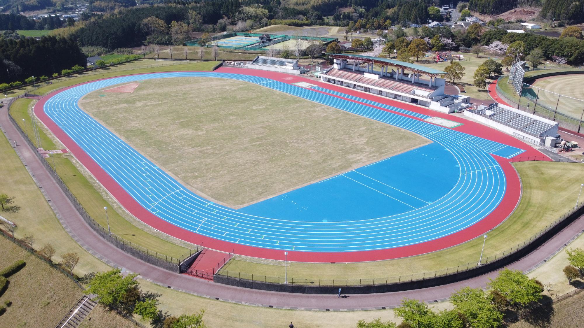 芝生のグラウンドやトラックなどがある小林総合運動公園陸上競技場の写真