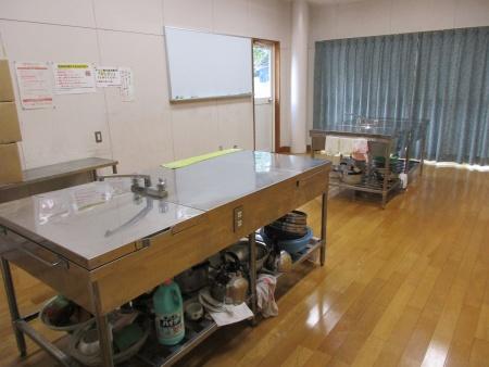 ステンレスの調理台とホワイトボードがある調理室の写真
