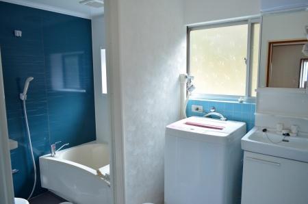 左奥に青い壁が美しいフロンティア荘の浴室と、その手前にある脱衣所に洗濯機と洗面台がある写真