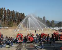 消防出初式の一斉放水で消防車から多量の水が発射されている写真