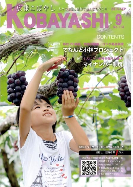 頭上の木に実っているブドウを鋏で収穫している女の子の写真が掲載された広報こばやし9月号の表紙