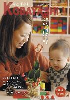 机上の小さな門松を見て笑顔を浮かべる女性と幼子の写真が掲載された広報こばやし1月号の表紙