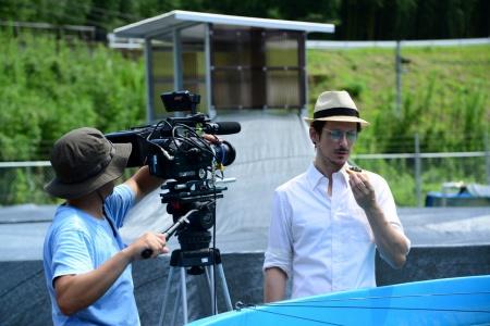 カメラマンが何かを手に持って見ている眼鏡をかけた西洋人の男性を撮影している、チョウザメ養殖場の写真