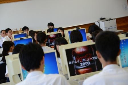 パソコンが並んだ教室で、モニターに映った越智さんのCMを見ている生徒たちの写真