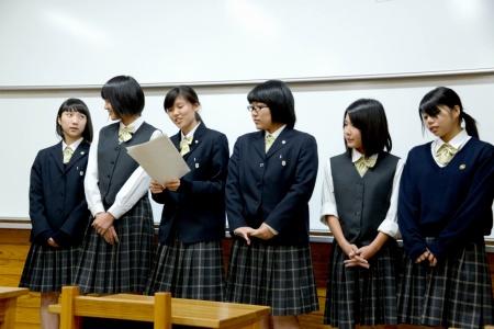 ホワイトボードの前で、女子生徒たちが並んで発表しているプレゼンテーションの写真