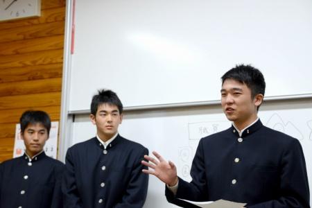 ホワイトボードの前で、男子生徒たちが並んで立っているプレゼンテーションの写真
