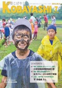 レインコートを着て笑顔で泥遊びをしている子供の写真が掲載された広報こばやし7月号の表紙