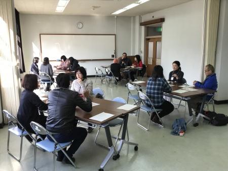 教室内でいくつかの班にわかれて椅子に腰かけ話をしている参加者たちの写真