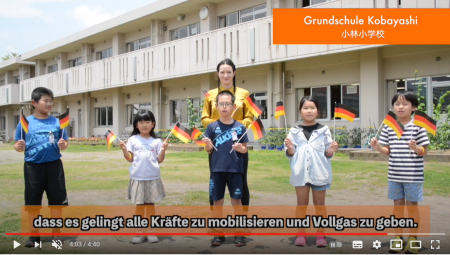 ドイツの国旗を持った5名の児童と女性が笑顔で並んでいるスクリーンショット