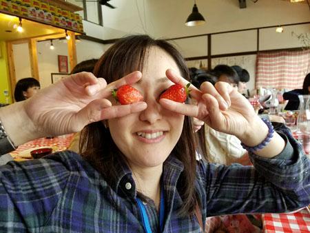 両手でそれぞれイチゴをつかみ、顔の目のあたりに重ねている女性の写真